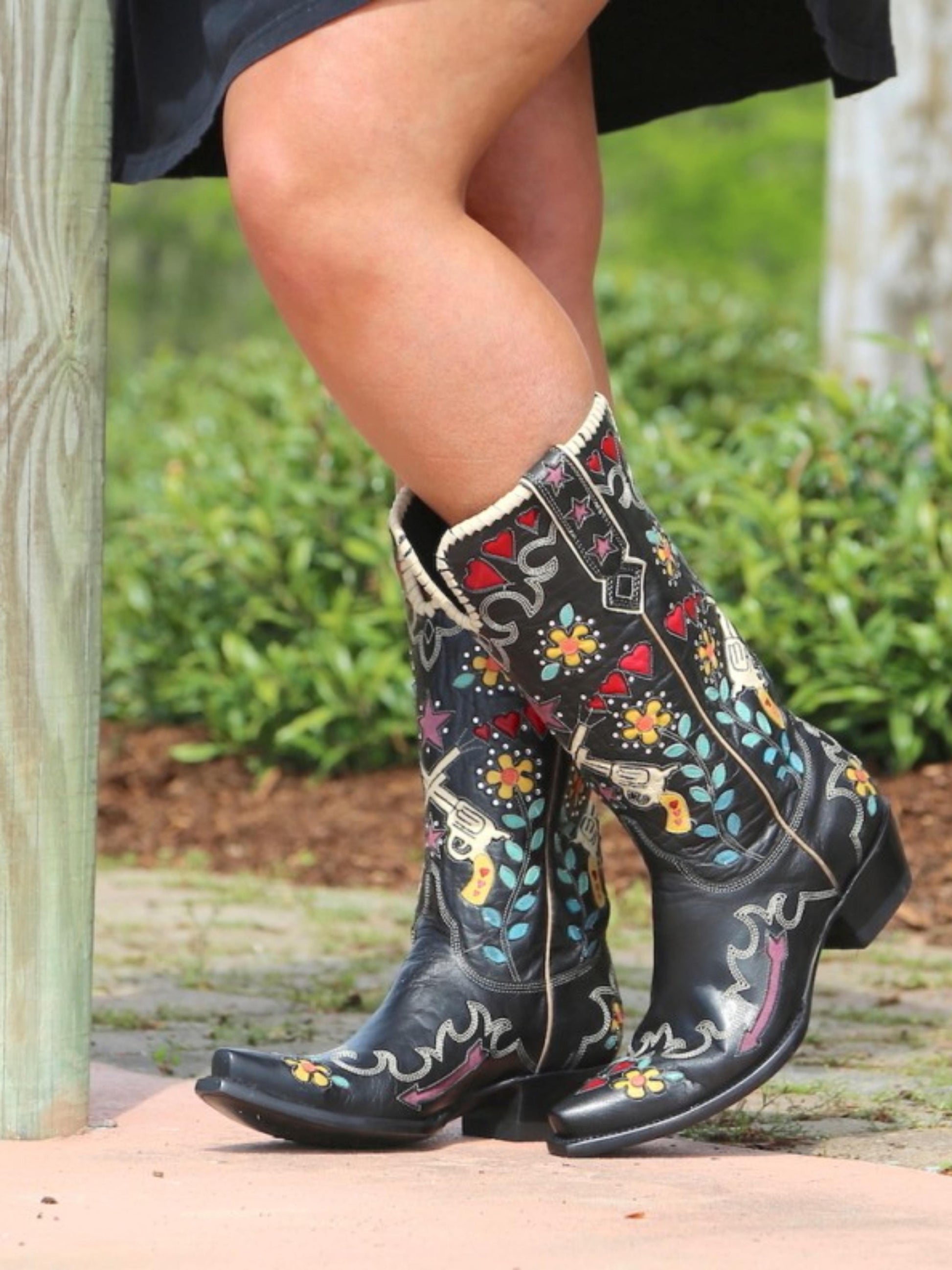 Black cowboy boots with colorful floral patterns.